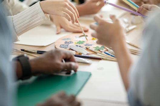 Hände, Zeichen- und Malerwerkzeuge auf dem Tisch
